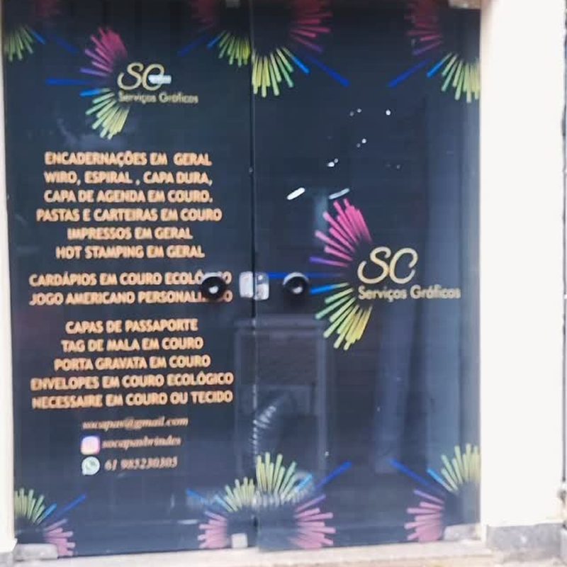 Fachada da loja SC Serviços Gráficos com a lista de serviços na porta